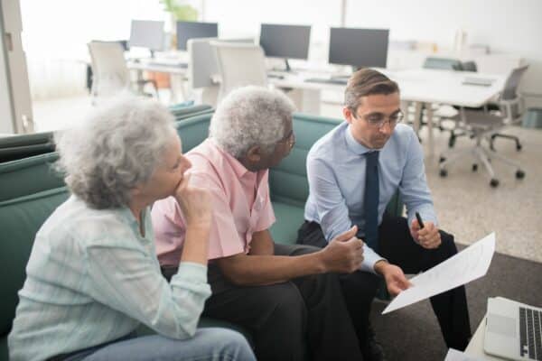 Couple senior avec un conseiller patrimonial pour arbitrer entre fonds euros et unités de compte en assurance vie